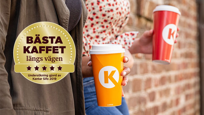 Röd och gul circle K mugg som hålls av två kvinnor